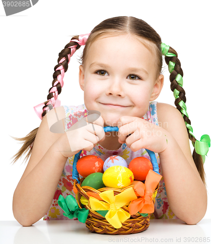 Image of Little girl with basket full of colorful eggs