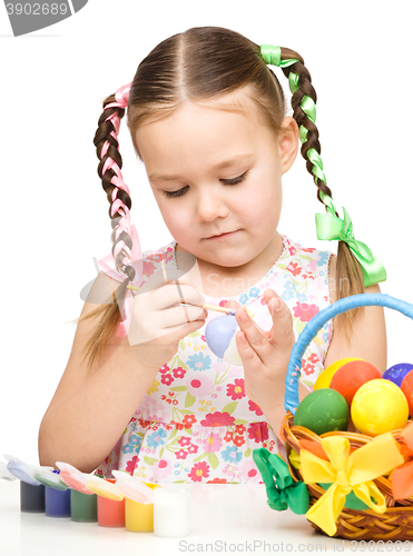 Image of Little girl is painting eggs preparing for Easter