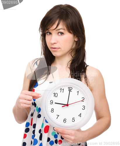 Image of Young woman is holding big clock