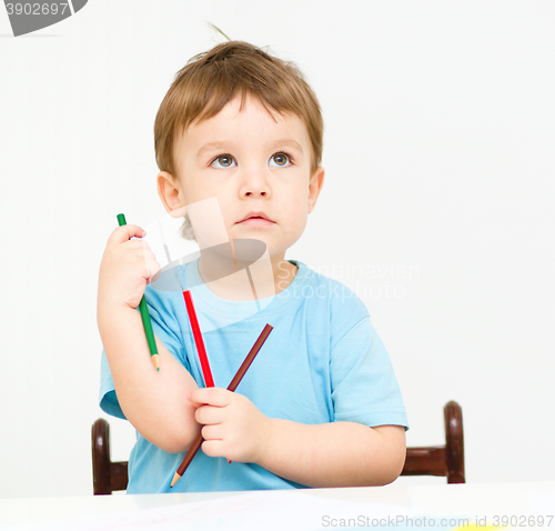 Image of Little boy is drawing on white paper