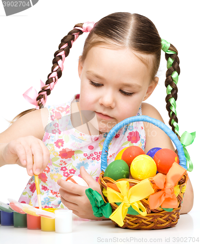 Image of Little girl is painting eggs preparing for Easter