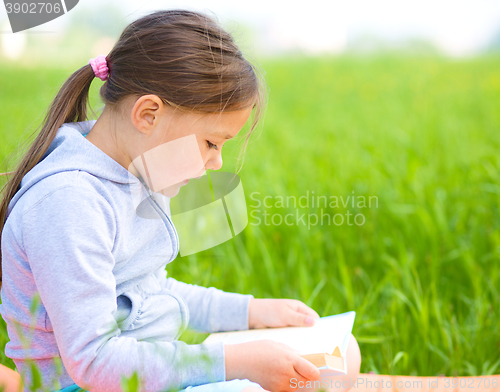 Image of Little girl is reading a book outdoors