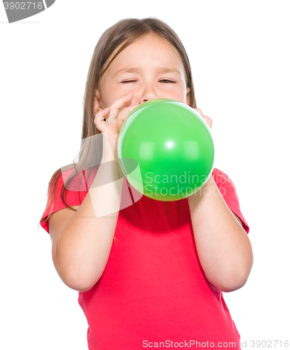 Image of Little girl is inflating green balloon