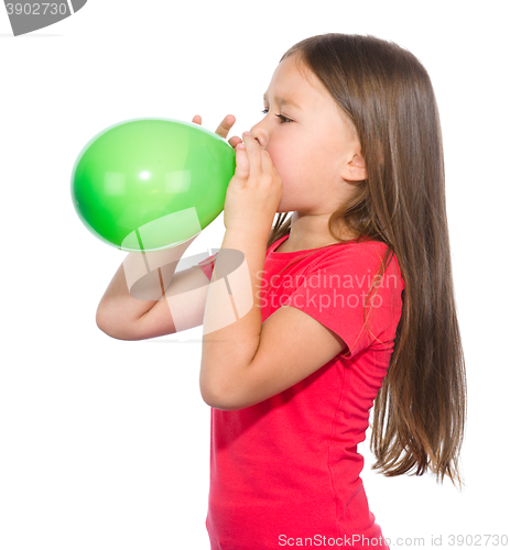 Image of Little girl is inflating green balloon