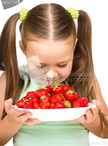 Image of Happy little girl is eating strawberries