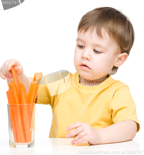 Image of Little boy is eating carrot