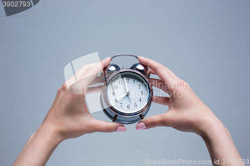 Image of The female hands and old style alarm clock 