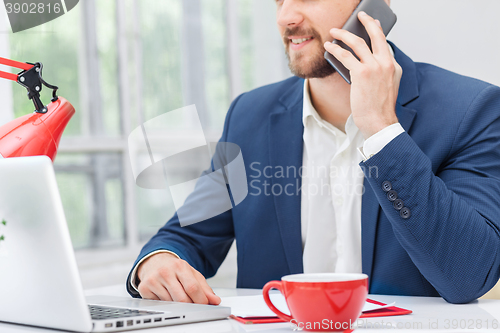 Image of Portrait of businessman talking on phone in office