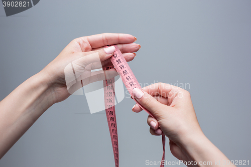 Image of The tape in female hands on gray background. Weight loss, diet