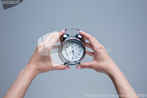 Image of The female hands and old style alarm clock 