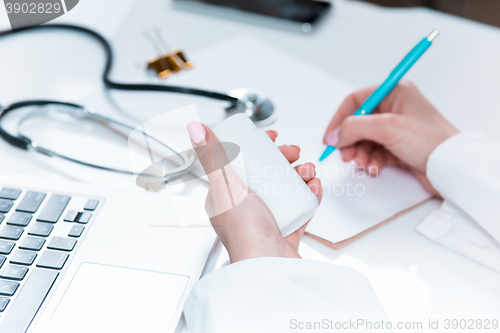 Image of The hands of doctor woman writing at the medical office