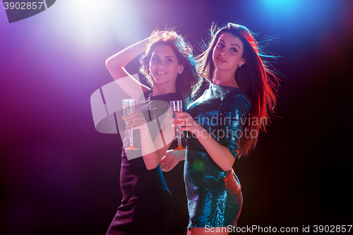 Image of Two beautiful girls dancing at the party drinking champagne