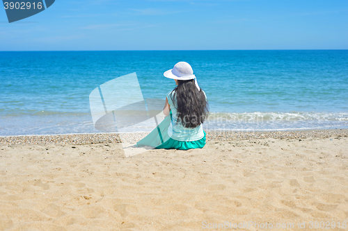 Image of Brunette with long hair turned away and sitting