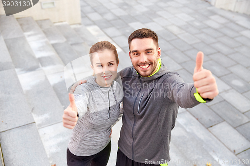 Image of smiling couple showing thumbs up on city street