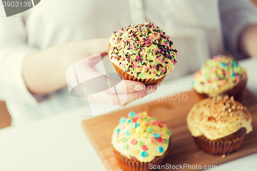 Image of close up of woman with glazed cupcakes or muffins