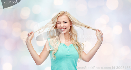 Image of smiling young woman holding strands of her hair