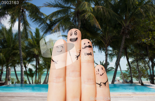 Image of close up of fingers with smiley faces on beach