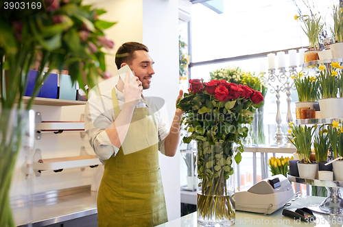 Image of man with smartphone and red roses at flower shop