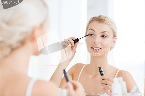 Image of woman with mascara applying make up at bathroom