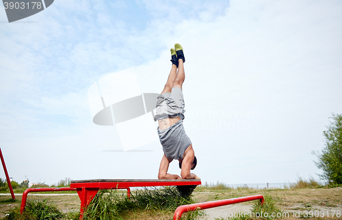 Image of young man exercising on bench outdoors