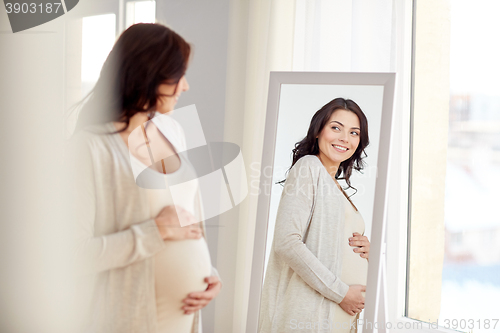 Image of happy pregnant woman looking to mirror at home