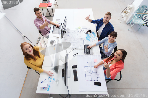 Image of creative team with computers showing thumbs up