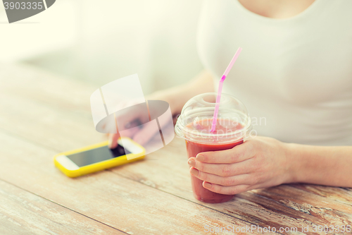 Image of close up of woman with smartphone and smoothie