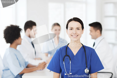 Image of happy doctor over group of medics at hospital