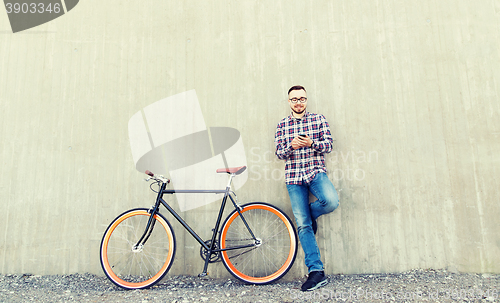 Image of hipster man in earphones with smartphone and bike