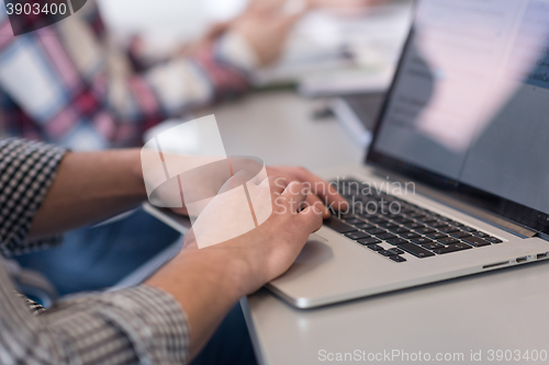 Image of close up of business man hands typing on laptop with team on mee