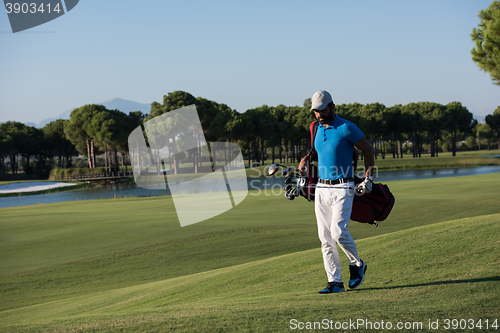 Image of golf player walking and carrying bag