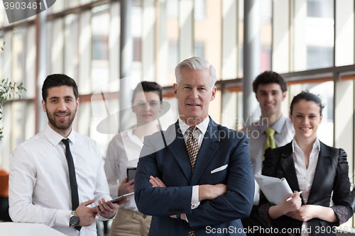 Image of portrait of senior businessman as leader  with group of people i