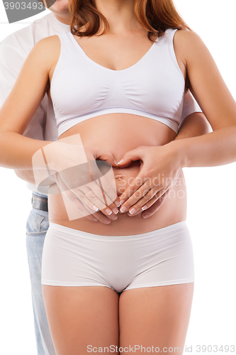 Image of Pregnant woman and man forming heart on baby bump