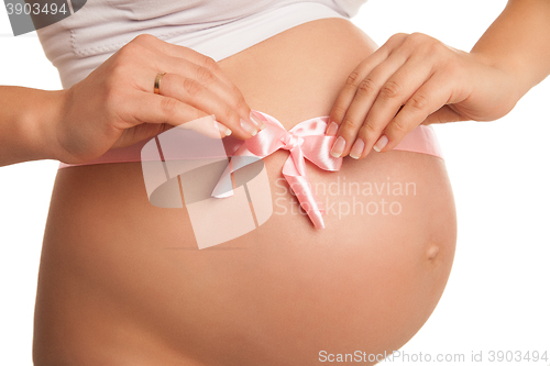 Image of Pregnant woman tummy with pink ribbon over white