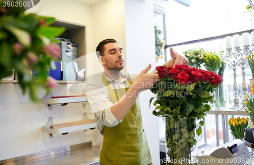 Image of smiling florist man with roses at flower shop