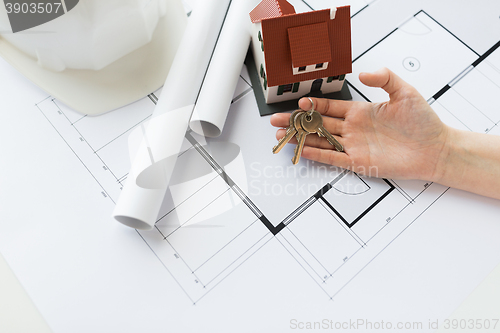 Image of close up of hand with house keys and blueprint