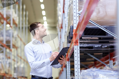 Image of happy businessman with clipboard at warehouse