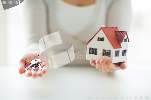 Image of close up of hands holding house model and keys