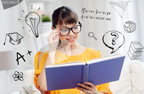 Image of smiling young asian woman reading book at home