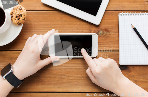 Image of close up of woman with smartphone on wooden table