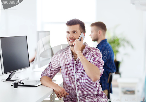 Image of happy creative man calling on cellphone at office