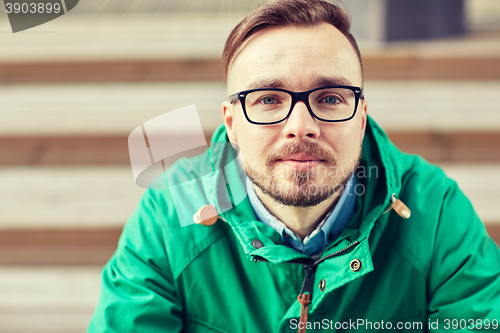 Image of happy young hipster man sitting on stairs in city