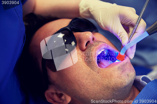 Image of close up of male patient with dental curing light