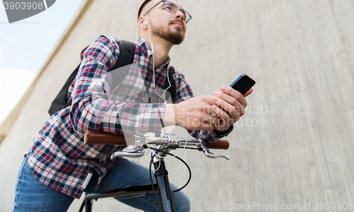 Image of hipster man in earphones with smartphone and bike