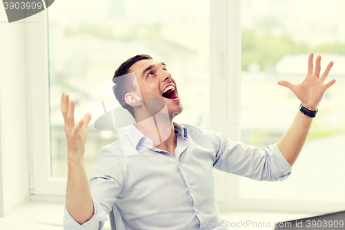 Image of happy businessman with laptop in office