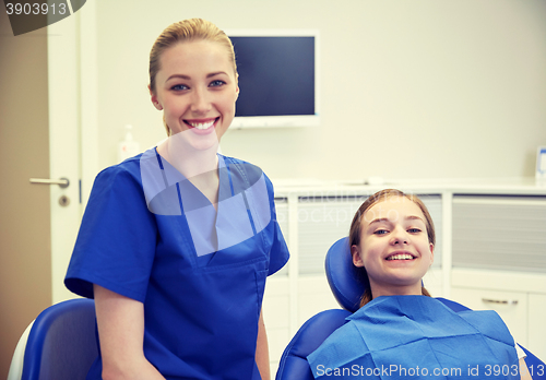 Image of happy female dentist with patient girl at clinic