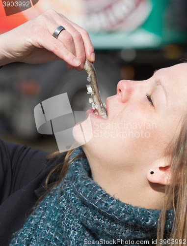 Image of Dutch woman is eating typical raw herring