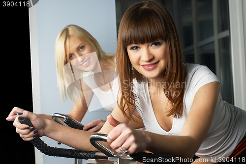 Image of Attractive girls on bicycle simulator in gym