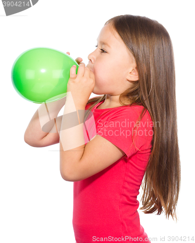 Image of Little girl is inflating green balloon