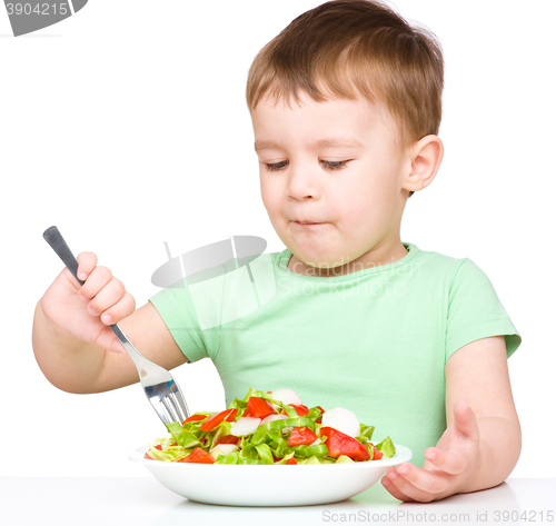 Image of Cute little boy is eating vegetable salad